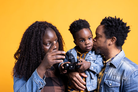 Proud father kissing his little cute toddler against background, showing affection while he plays. Pleased happy african american dad caressing his young child in studio.の写真素材