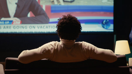 Person relaxing on couch watching VOD channel on large television set in living room. Zoom in shot on cord cutter entertained by streaming service program broadcasted on smart TV in home theatreの写真素材