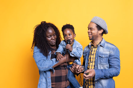 African american parents teaching their baby boy how to sing on microphone, learning to perform...