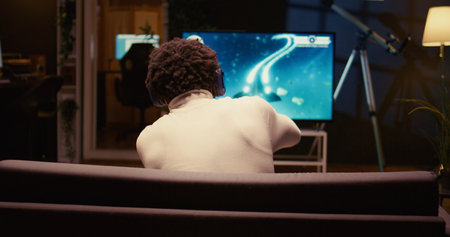 Man uses cloud gaming service to play demanding SF videogame on television set. Panning shot of...