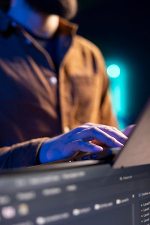 Teleworking programmer doing software debugging using laptop, checking flaws in lines of code displayed on PC monitors. IT admin in apartment fixing coding issues using notebook, close upの写真素材