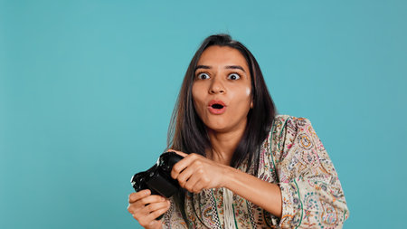 Happy gamer celebrating after winning game on gaming console, studio background. Delighted woman bragging after being victorious in videogame, defeating all enemies using gamepad, camera Bの写真素材