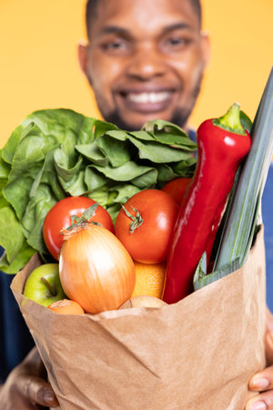 Enthusiastic shopper promoting green bio groceries and nutrition, glowing with pride over his...