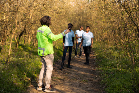 Rescue squad leader guiding people through the woods to track footsteps during searching operation...
