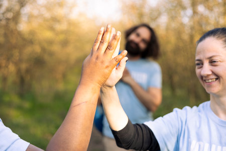 Happy team of environmentalists share high five with each other, saying congratulations and being...