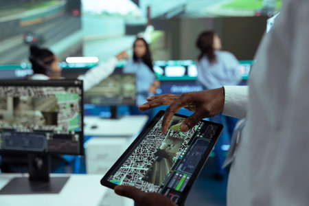 African american male supervisor handles monitoring activity via CCTV footage and satellite...