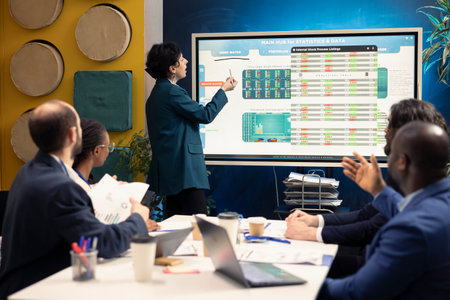Business partners examining annual sales reports in corporate meeting, developing internal...