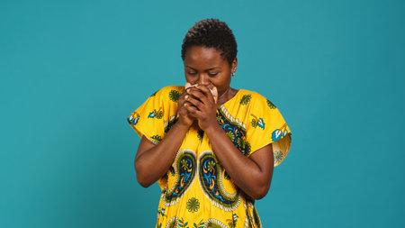 Woman in traditional ethnic clothing drinks a sip from coffee cup, serving a fresh caffeine beverage with amazing roasted aroma. Happy pleased girl drinking a refreshment in studio. Camera A.の写真素材