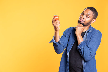 Vegan person admiring a bio ethically sourced tomato and enjoying the fresh smell in studio, thinking of a food recipe to cook. Zero waste enthusiast supports sustainable lifestyle.の写真素材