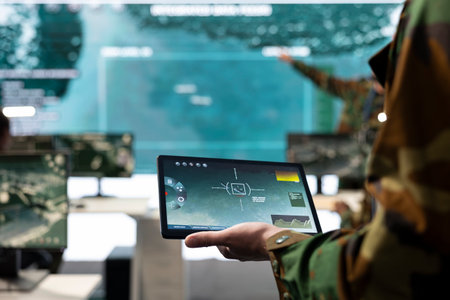 Army conscript detecting targets on a satellite world map to ensure national safety, operates on tablet in military power base of operations. Examines battlefield real time data. Close up.の写真素材