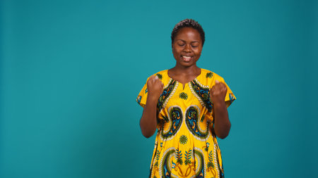 Cheerful woman hoping for something good to happen to her, cheering and feeling hopeful in studio. Positive smiling young adult posing with confidence against background. Camera B.の写真素材