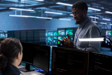 African american man in data center using diagnostic tools and system monitoring software to...