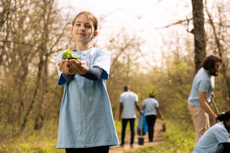 Little kid volunteer showing small seedling with natural soil in her hands, new habitat in the forest. Small girl fighting for nature preservation, cultivating consciousness and with activists.の写真素材
