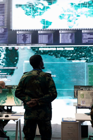 Infantry unit recruit analyzing important battlefield data on big screen, gathering information for future special operations or missions. Military personnel reviewing gps tracking satellite imagery.の写真素材