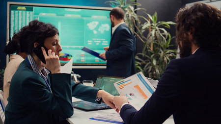Business manager talking on phone call with the accountant to see the stock market trends progress, calling her associate to obtain more funding for a developing project. Boardroom. Camera B.の写真素材