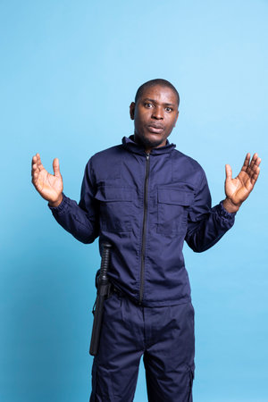 African american security agent acting surprised and in shock in front of the camera, wearing guarding uniform and baton. Officer working on protecting people and securing places.の写真素材