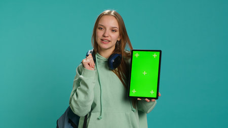 Portrait of woman presenting tablet with chroma key display, isolated over studio background. Young girl creating promotion with blank copy space mockup digital device, camera Aの写真素材