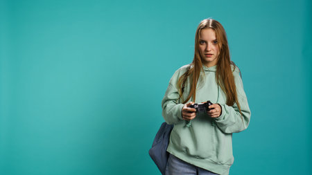 Young girl spamming controller buttons, disappointed after receiving game over screen. Woman upset after losing videogame, playing with gamepad, studio background, camera Bの写真素材