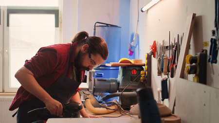 African american carpenter in joinery watching apprentice using orbital sander on lumber. Team in woodworking shop using angle grinder to create wooden decorations, refining wood objects, camera Bの写真素材