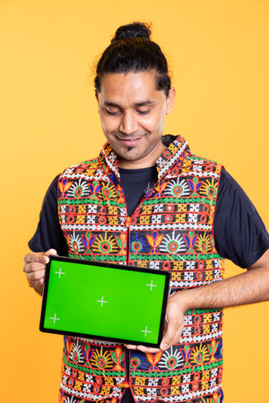 Portrait of upbeat influencer presenting isolated screen tablet, studio background. Joyous technology expert showcasing chroma key deviceの写真素材