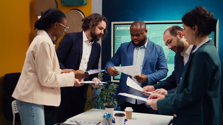 Diverse business affiliates studying market trends by reviewing finances on archived papers, look...