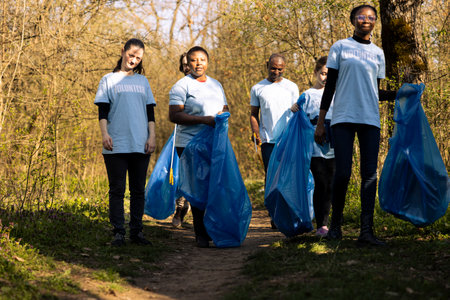 Team of volunteers doing community service to collect garbage and help preserve natural ecosystem, gathering to clean the forest. Diverse group fighting pollution and illegal dumping.の写真素材