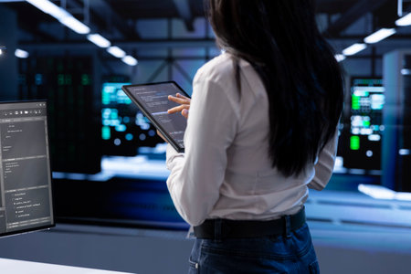 Engineer doing yearly checkup to prolong data center electronics life span and avoid downtime. Woman in server room monitoring server infrastructure components using tabletの写真素材