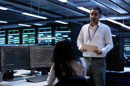 Data center inspector asks worker to show him emergency procedures paperwork, ensuring company is protected against system failure. Supervisor in server hub verifies industry regulations are respectedの写真素材