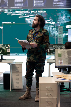 Military personnel examining live satellite imagery on a big screen in army base of operations,...