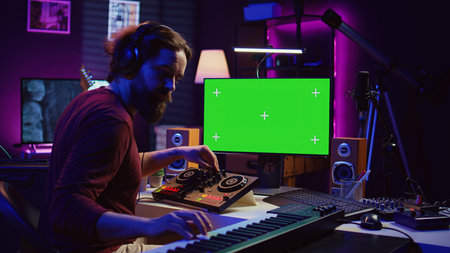 Music producer songwriter mixing piano key notes in home studio, operating with greenscreen monitor...