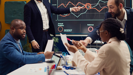 Project team colleagues examining sales infographics on presentation, reviewing annual reports to understand what needs to change in order to expand the business internationally.の写真素材