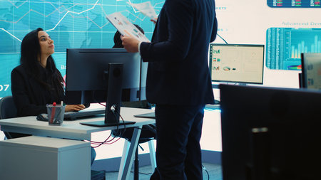General director CEO sharing insight about a new development strategy with his employees, showing important data reports to analyze organizational activity status in a control room. Camera A.の写真素材