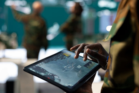 Trooper monitoring the operational area via CCTV surveillance footage, using a tablet to find any threats in command post power base. Anti terrorism army division headquarters. Close up.の写真素材