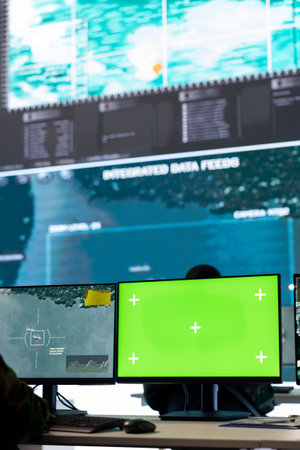 Intelligence analyst reviews air and sea activity next to an isolated mockup display, following gps coordinates of vessels anchoring in the ports. Army trooper working in monitoring room.の写真素材