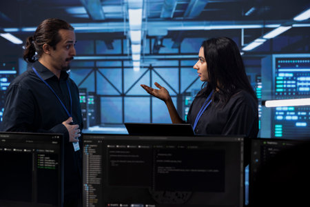 Programmers in server room discussing next steps after checking recovery plan and monitoring energy...