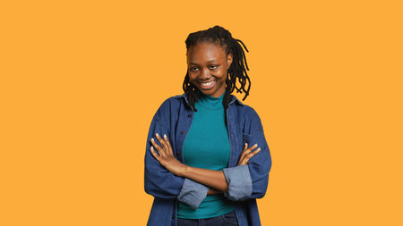 Cheerful teenager having positive wellbeing, feeling optimistic, isolated over studio background. Portrait of jolly woman with good mood standing proud, feeling confident, camera Aの写真素材