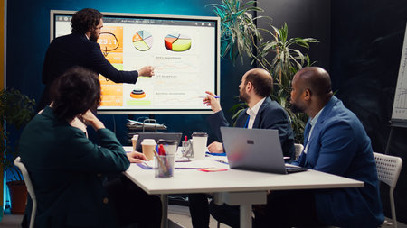 Project manager does a market research presentation for his team, better understanding of the situation. Associates work on technology or infrastructure investments to fulfill objectives. Camera B.の写真素材