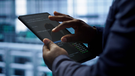 Software developer does yearly checkup using tablet to prolong data center electronics life span. Close up shot of worker in server room monitoring server infrastructure using digital device, camera Aの写真素材