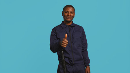 Happy security guard doing thumbs up sign gesturing with finger, preventing public access in restricted area. Portrait of smiling bodyguard doing positive hand gesture, studio background, camera Bの写真素材