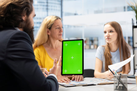 Clients looking over personalized planning guide on isolated screen tablet made by financial advisor. Accountant optimizing living expenses for customers using chroma key deviceの写真素材