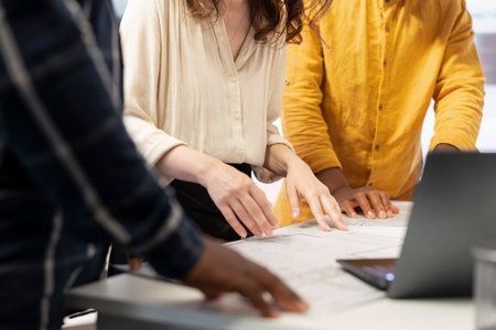 Real estate expert advising entrepreneurs about new investment opportunity with property leasing, meeting on an office tour. Clients and realtor evaluating blueprints of high class office. Close up.の写真素材