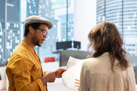 Client sharing her office space layout vision with real estate agent, planning to sign a leasing contract for the high class property. Realtor showing the design during a office tour.の写真素材