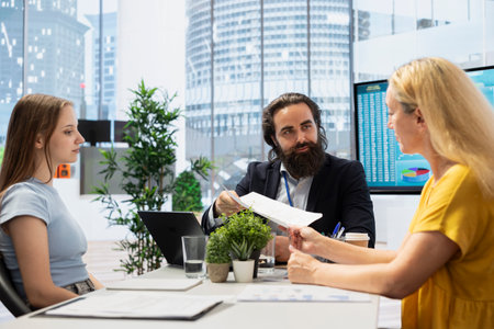 Financial advisor establishing emergency fund for woman and gen Z girl before investing. Agent discussing in office meeting with clients, providing financial security in case of unexpected emergenciesの写真素材