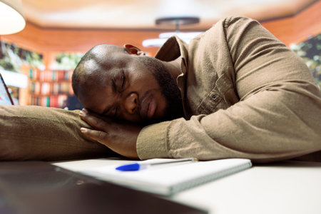 Exhausted businessman taking a nap and resting at home desk setup, getting some sleep while he works remotely on business operations. Freelancer dealing with burnout and fatigue.の写真素材
