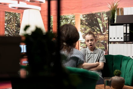 Rebellious teenager venting in frustration during counseling session, raising issues of bullying and social pressure. The therapist offers negative behavior and arrogance, anger management.の写真素材