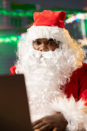 Father Christmas is navigating the web checking on children wish lists using his laptop. Festive North Pole cabin is filled with holiday cheer and online activity this x mas, checking the world map.の写真素材
