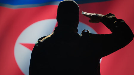 Secret intelligence agent doing saluting hand gesture towards North Korea flag in war room, showing respect. Special operations spy with mask serving country, doing honoring gesturing, camera Aの写真素材