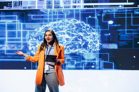 Upbeat programmer using tablet during presentation, exploring ways emerging AI technologies can enhance businesses. Jolly woman at event presents artificial intelligence using device and microphoneの写真素材