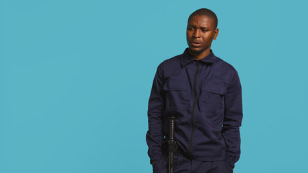 Portrait of security guard looking around while overseeing premises. Private law enforcement worker doing surveillance job, inspecting location, studio backdrop, camera Bの写真素材