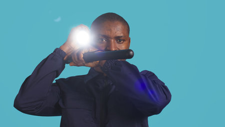 Headshot portrait of security staff member evicting trespassers with baton after spotting them with flashlight. Close up of patrolling agent using truncheon and lantern to evict intruders, camera Bの写真素材